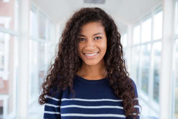 Portrait of a happy afro american woman standing in university hall and looking at camera